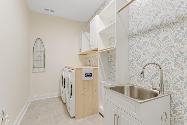 washroom featuring visible vents, washing machine and clothes dryer, cabinet space, a sink, and baseboards