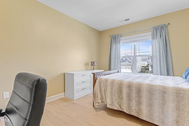 bedroom with baseboards, visible vents, and light wood finished floors