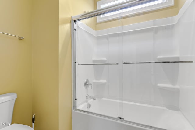 bathroom featuring combined bath / shower with glass door and toilet