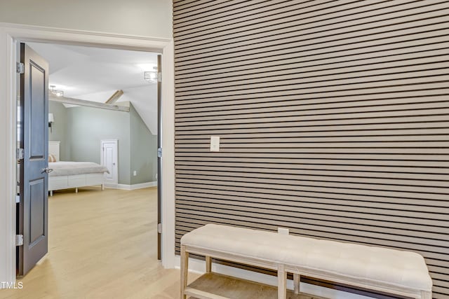 corridor featuring baseboards, vaulted ceiling, and light wood finished floors