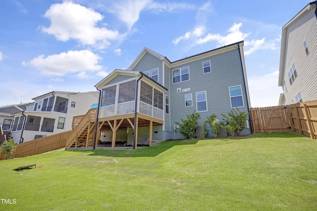 back of property with a fenced backyard, a yard, a sunroom, and stairway