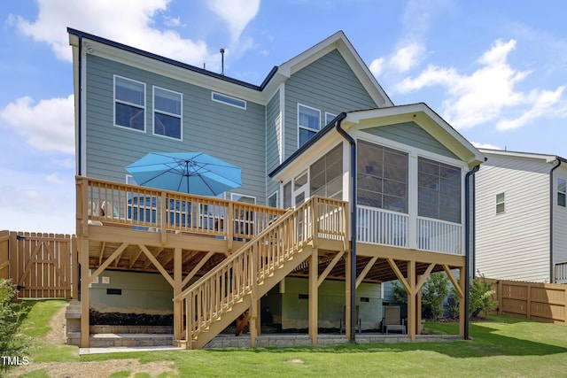 back of house featuring fence, a deck, a sunroom, stairs, and a lawn