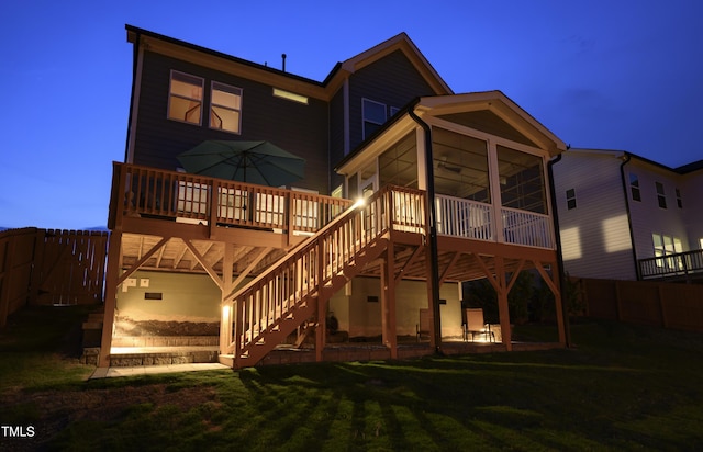 rear view of house featuring a lawn, fence, a sunroom, and a deck