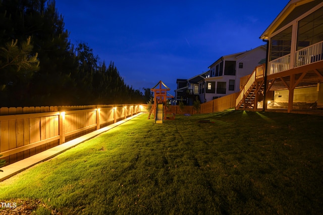 yard at night with stairs, a fenced backyard, and playground community