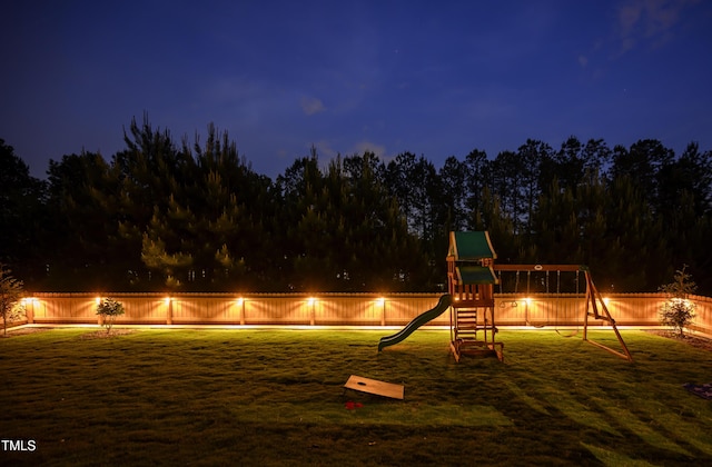 playground at night with a yard, playground community, and fence