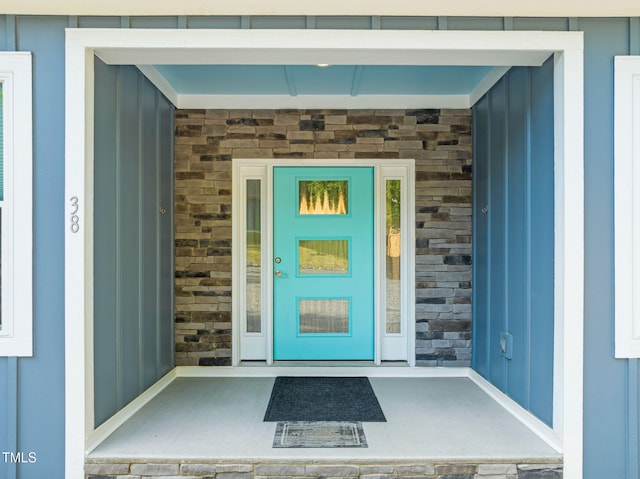 doorway to property with board and batten siding and stone siding