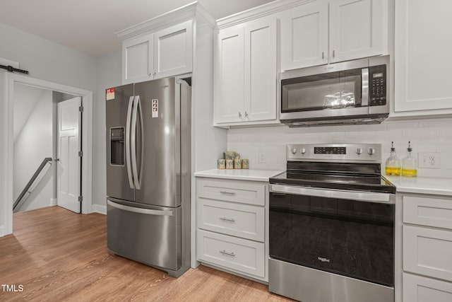 kitchen featuring light wood-type flooring, light countertops, decorative backsplash, and stainless steel appliances