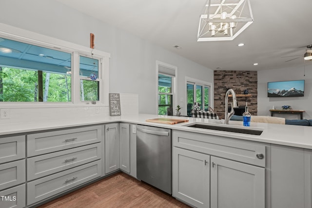 kitchen featuring wood finished floors, gray cabinets, a sink, and dishwasher