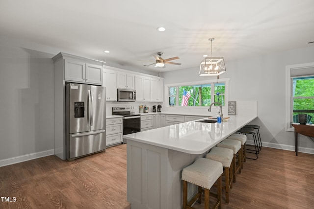 kitchen featuring a sink, stainless steel appliances, recessed lighting, a peninsula, and a kitchen bar