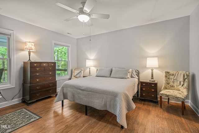 bedroom with baseboards, wood finished floors, and multiple windows