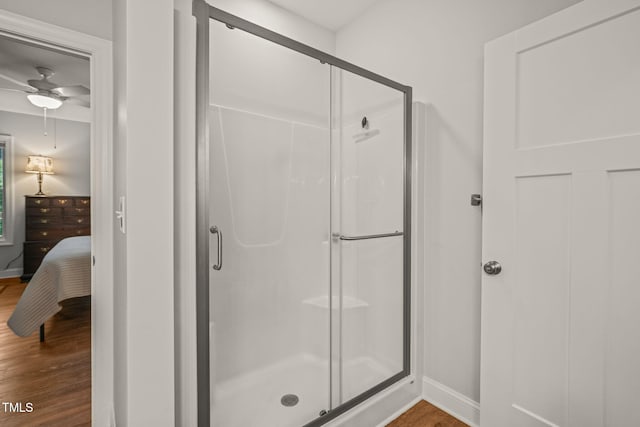 full bath with baseboards, a shower stall, and wood finished floors