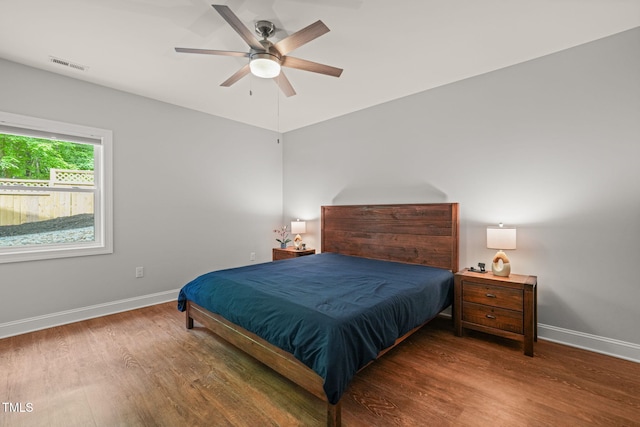 bedroom featuring baseboards, ceiling fan, wood finished floors, and visible vents
