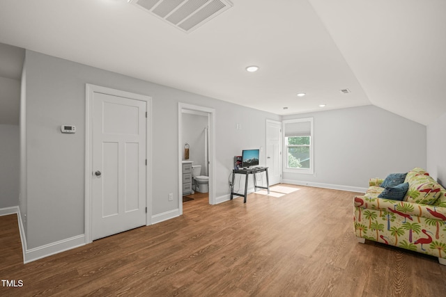 living area with baseboards, vaulted ceiling, wood finished floors, and visible vents