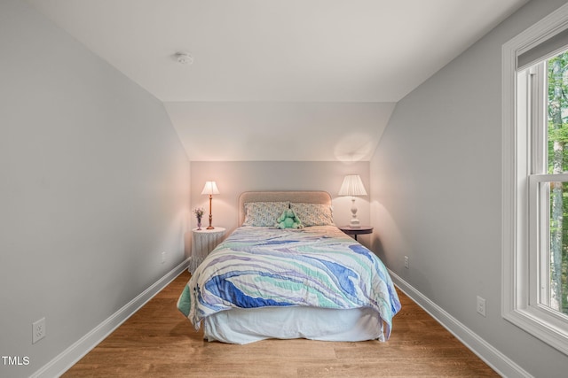bedroom featuring baseboards, vaulted ceiling, and wood finished floors