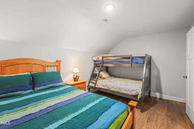 bedroom featuring baseboards, vaulted ceiling, wood finished floors, and visible vents