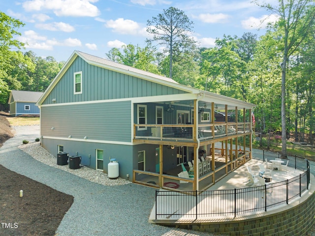 rear view of house with board and batten siding, a wooden deck, a patio area, central air condition unit, and fence