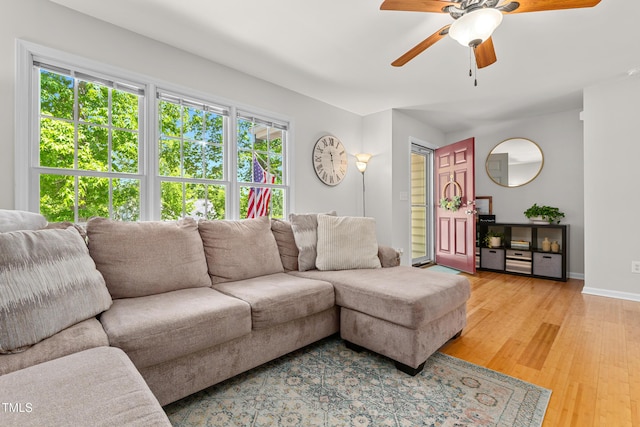 living area featuring ceiling fan, baseboards, and light wood finished floors