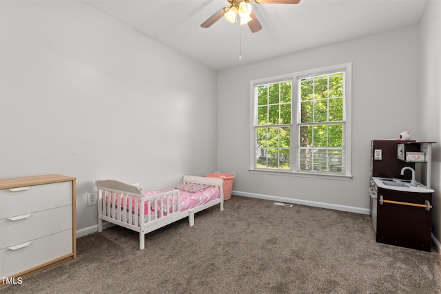 carpeted bedroom with visible vents, a sink, baseboards, and a ceiling fan