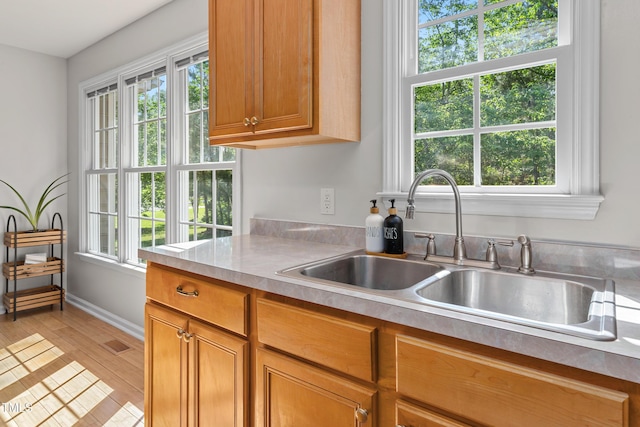 kitchen with plenty of natural light, a sink, brown cabinets, and light countertops