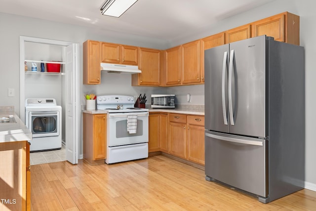 kitchen with washer / dryer, light countertops, under cabinet range hood, light wood-style flooring, and stainless steel appliances