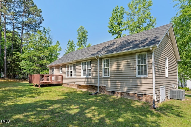 rear view of property with crawl space, roof with shingles, a wooden deck, cooling unit, and a yard