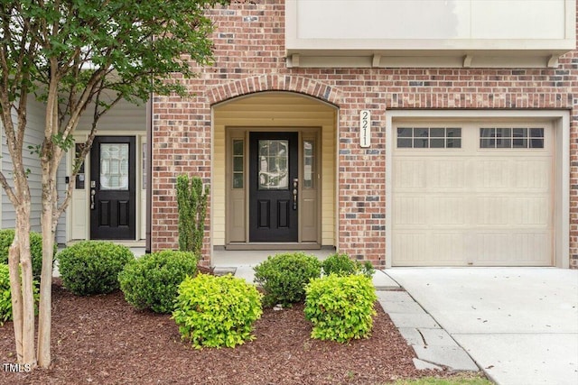 doorway to property featuring brick siding, concrete driveway, and an attached garage