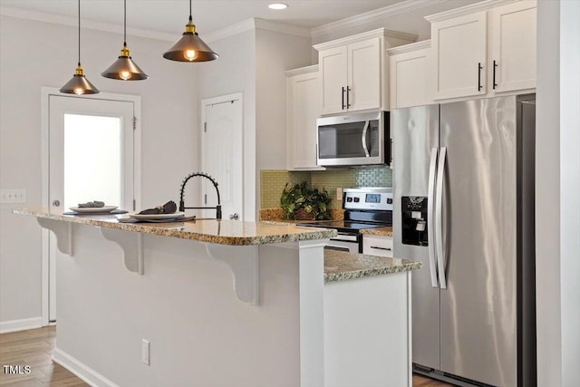 kitchen featuring appliances with stainless steel finishes, a sink, white cabinetry, crown molding, and light stone counters