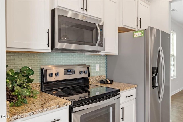 kitchen with stainless steel appliances, white cabinets, backsplash, and light stone countertops