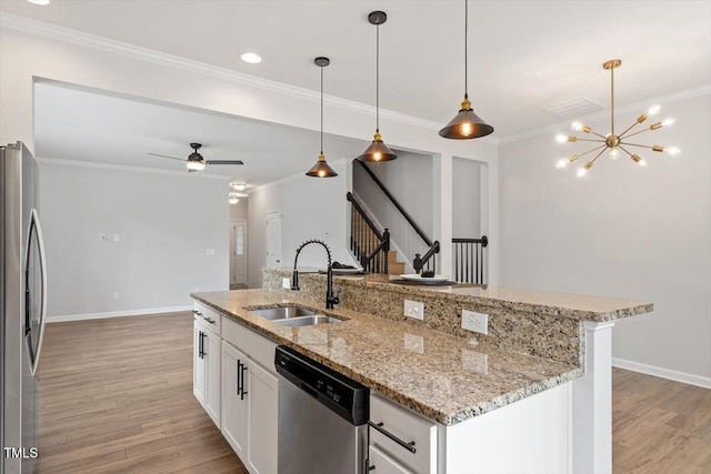kitchen featuring stainless steel appliances, a sink, light wood-type flooring, an island with sink, and crown molding
