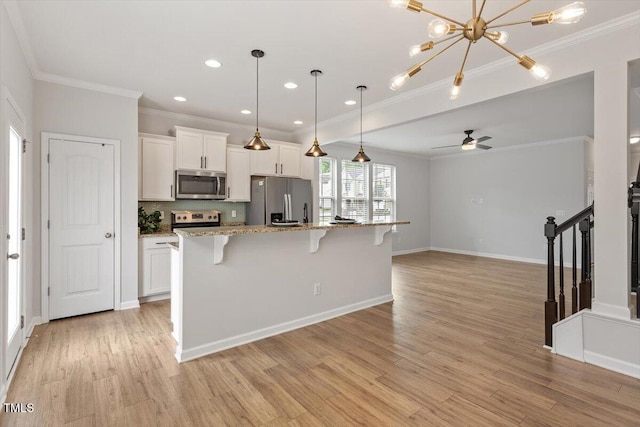 kitchen featuring stainless steel appliances, ornamental molding, a kitchen breakfast bar, white cabinetry, and light wood finished floors