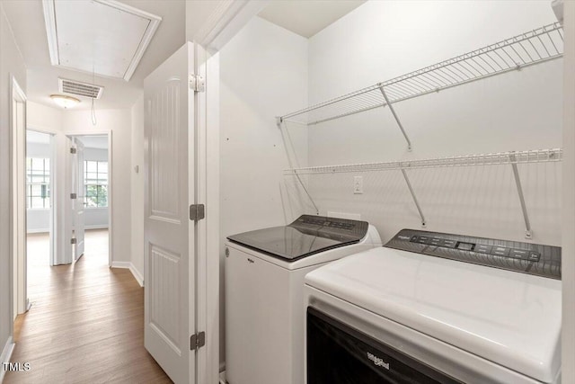 laundry area with attic access, washing machine and clothes dryer, light wood finished floors, and baseboards