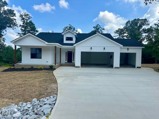 297 Dry Branch Dr, Kenly, NC 27542 - modern inspired farmhouse with concrete driveway, a porch, and an attached garage