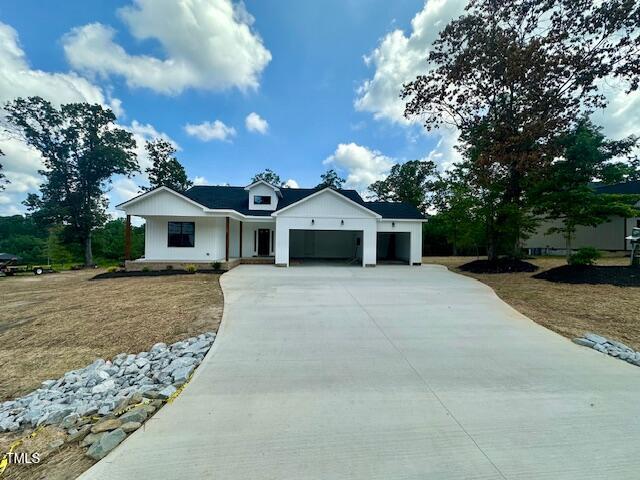 297 Dry Branch Dr, Kenly, NC 27542 - modern farmhouse style home featuring concrete driveway, an attached garage, and a front yard