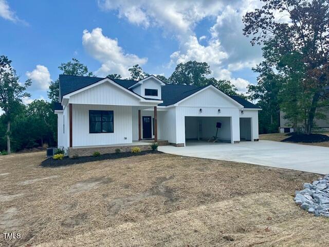 297 Dry Branch Dr, Kenly, NC 27542 - modern farmhouse style home featuring a porch, concrete driveway, and an attached garage