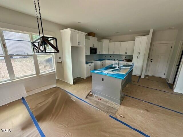 297 Dry Branch Dr, Kenly, NC 27542 - kitchen with a center island with sink, black microwave, white cabinets, and hanging light fixtures