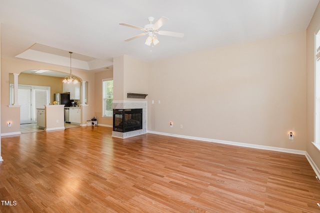209 Mccarthy Dr, Clayton, NC 27527 - unfurnished living room with arched walkways, a tray ceiling, light wood-style flooring, and ceiling fan