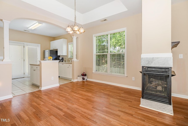 209 Mccarthy Dr, Clayton, NC 27527 - kitchen with freestanding refrigerator, light wood-style flooring, white cabinetry, arched walkways, and ornate columns