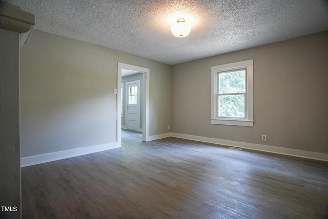 spare room featuring dark wood-style flooring, baseboards, and a textured ceiling