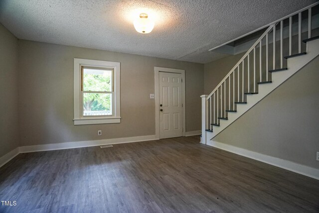 entryway with a textured ceiling, wood finished floors, stairs, and baseboards
