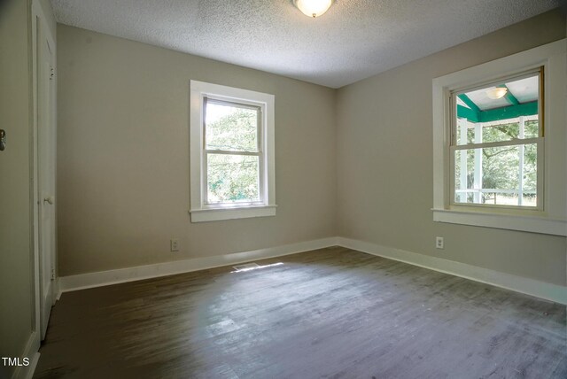 empty room featuring dark wood-style flooring, a textured ceiling, and baseboards