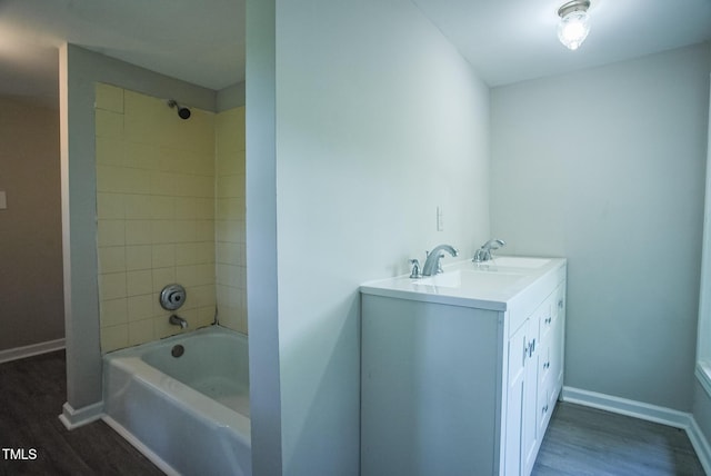 bathroom featuring wood finished floors, a sink, baseboards, and shower / tub combination