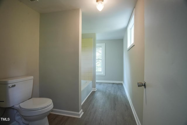full bath featuring wood finished floors, toilet, baseboards, a bathtub, and a shower