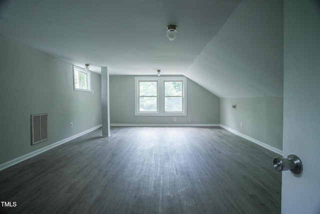 additional living space with dark wood-type flooring, vaulted ceiling, and baseboards