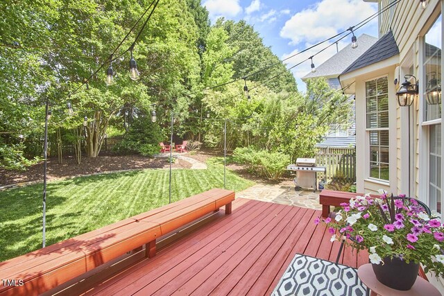 wooden terrace with a fenced backyard, a lawn, and grilling area