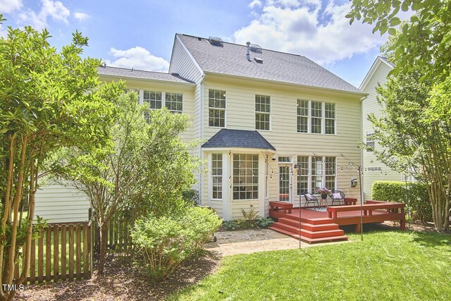 rear view of property with a lawn, fence, a wooden deck, and a shingled roof