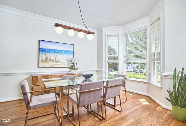 dining space featuring baseboards, visible vents, ornamental molding, and wood finished floors