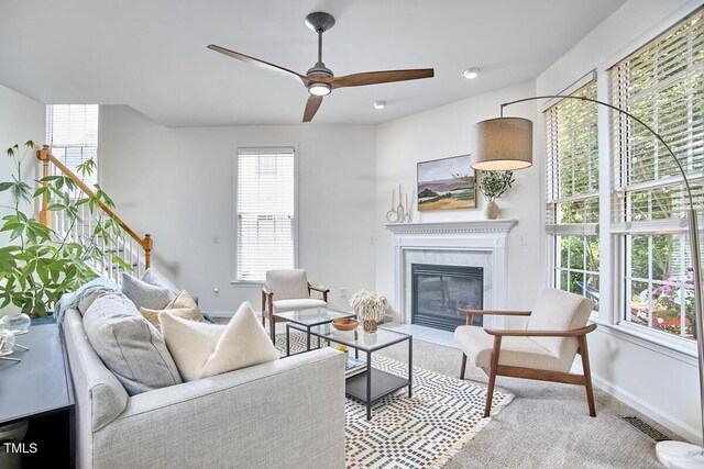 carpeted living area with baseboards, ceiling fan, visible vents, and a fireplace