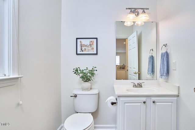 half bath with vanity, baseboards, and toilet