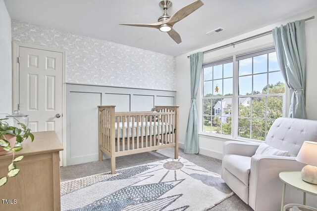 bedroom featuring visible vents, carpet floors, baseboards, a decorative wall, and wallpapered walls
