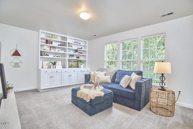 living area with baseboards, light carpet, and visible vents